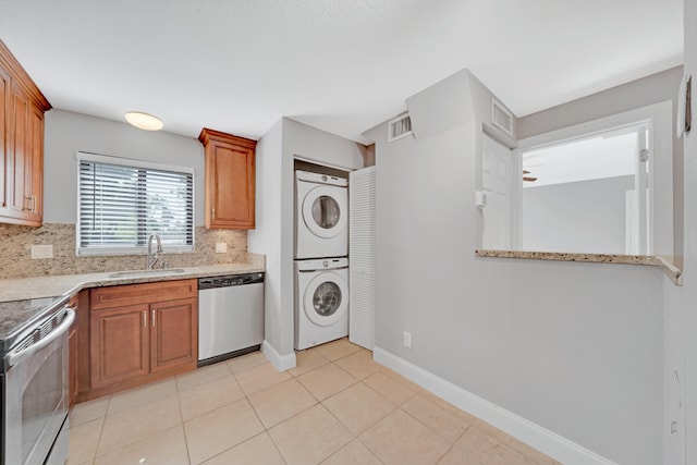 kitchen featuring light tile patterned flooring, backsplash, stacked washer and clothes dryer, electric range, and dishwasher