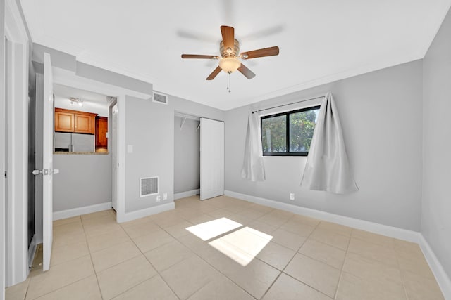 unfurnished bedroom with ceiling fan, stainless steel refrigerator with ice dispenser, a closet, crown molding, and light tile patterned flooring