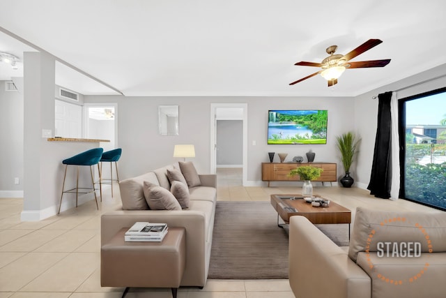 living room with ceiling fan, crown molding, and light tile patterned flooring