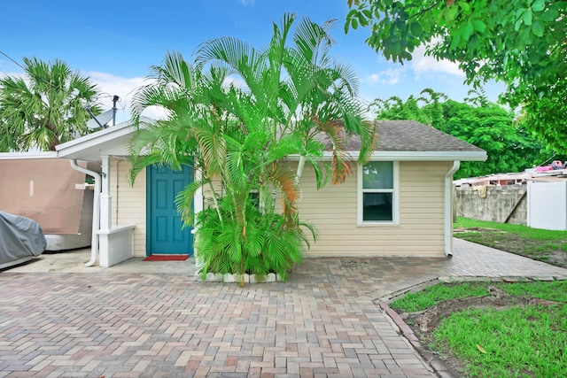 rear view of house with fence and a shingled roof