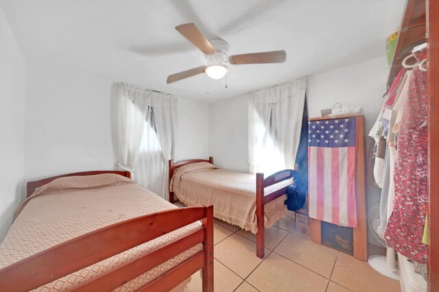 bedroom with ceiling fan, light tile patterned floors, and multiple windows