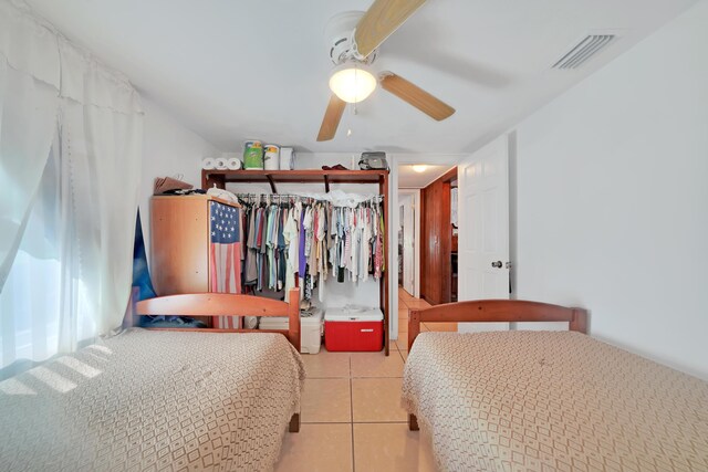 tiled bedroom featuring ceiling fan and a closet