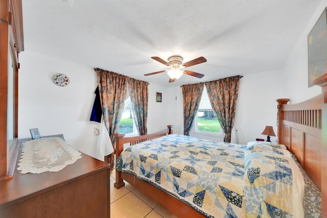 bedroom with a textured ceiling, ceiling fan, light tile patterned floors, and multiple windows