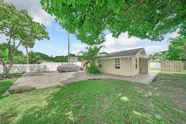 rear view of property featuring a yard, a patio area, and fence