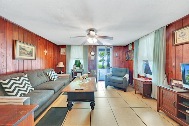 tiled living room with a textured ceiling, wood walls, and ceiling fan