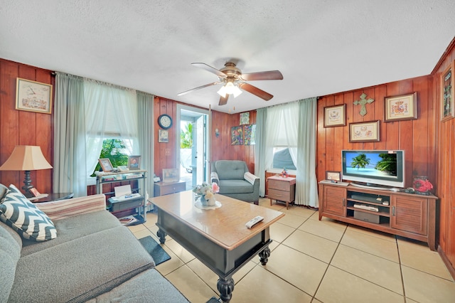 tiled living room with wood walls, ceiling fan, and a textured ceiling