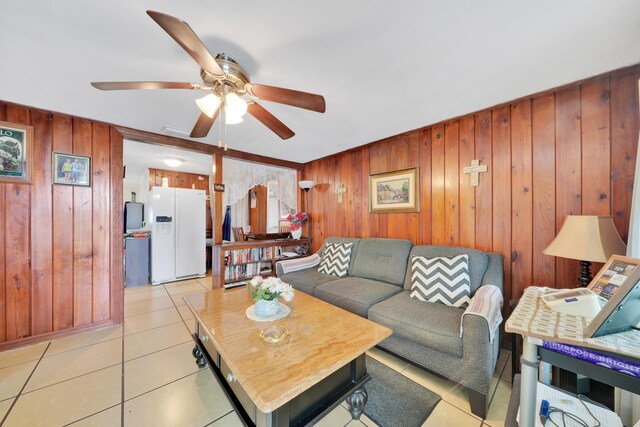 tiled living room with wood walls, ceiling fan, and ornamental molding