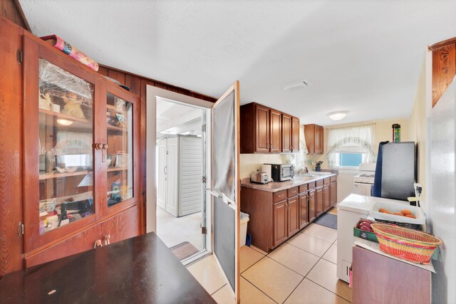 kitchen with light tile patterned floors, white gas stove, and sink