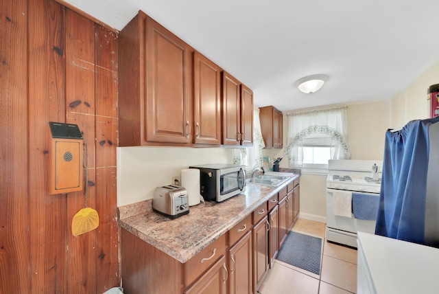 kitchen featuring light tile patterned floors, gas range gas stove, a sink, light countertops, and stainless steel microwave