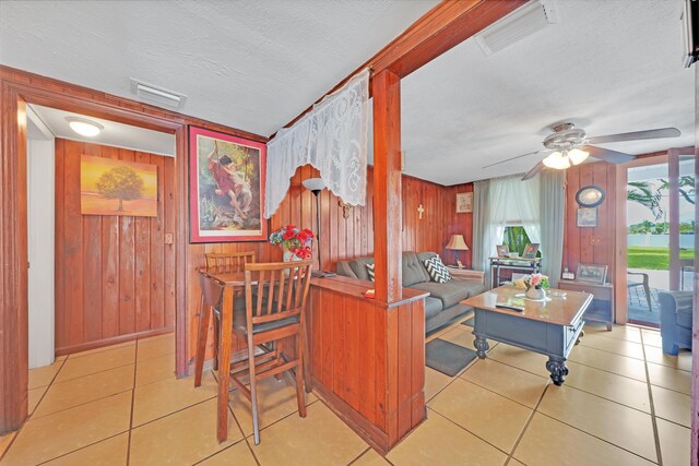 kitchen featuring ceiling fan, wooden walls, light tile patterned flooring, and a textured ceiling