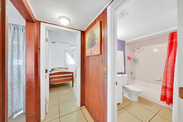 bathroom featuring shower / bath combination with curtain, toilet, a textured ceiling, and tile patterned flooring