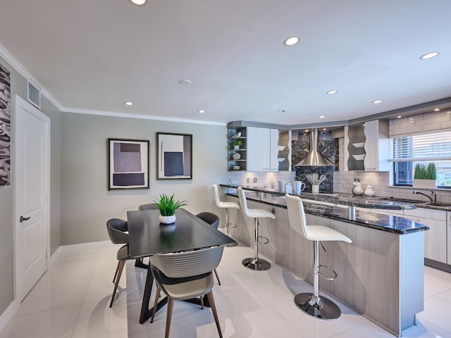 kitchen featuring backsplash, light tile patterned flooring, crown molding, and a kitchen breakfast bar