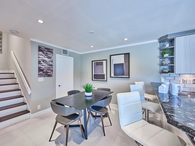 dining space featuring light tile patterned floors and crown molding