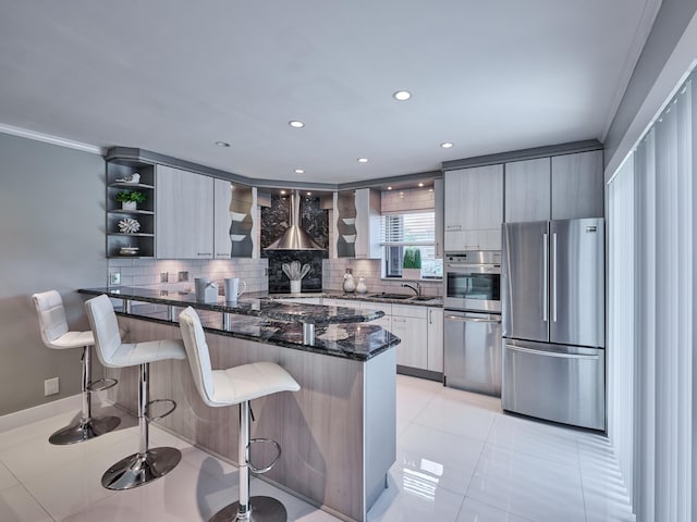 kitchen featuring a breakfast bar area, backsplash, dark stone counters, crown molding, and appliances with stainless steel finishes