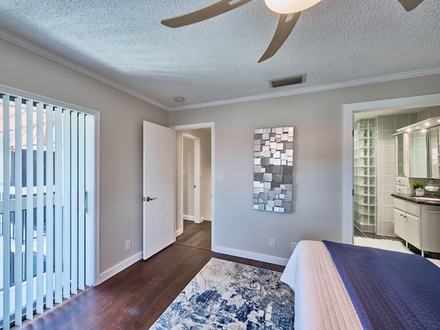 bedroom featuring ceiling fan, a textured ceiling, dark hardwood / wood-style floors, ensuite bathroom, and crown molding