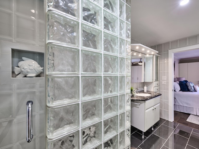 bathroom with tile walls, vanity, tile patterned flooring, and walk in shower