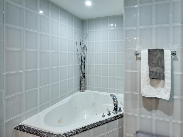 bathroom featuring a relaxing tiled tub and tile walls