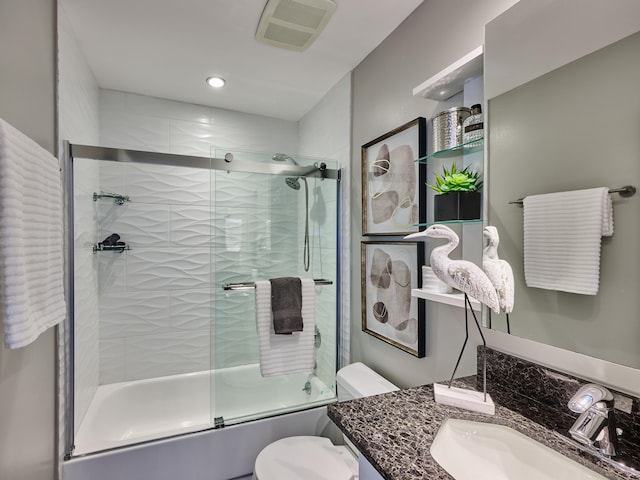 full bathroom featuring vanity, enclosed tub / shower combo, and toilet