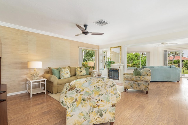 living room with crown molding, plenty of natural light, ceiling fan, and light hardwood / wood-style floors