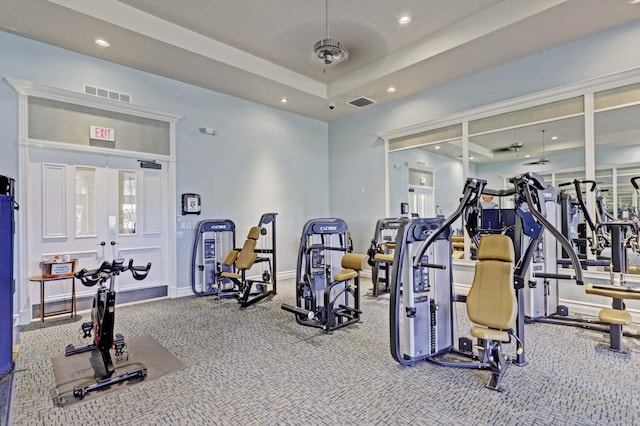 workout area featuring carpet, ceiling fan, french doors, and a raised ceiling