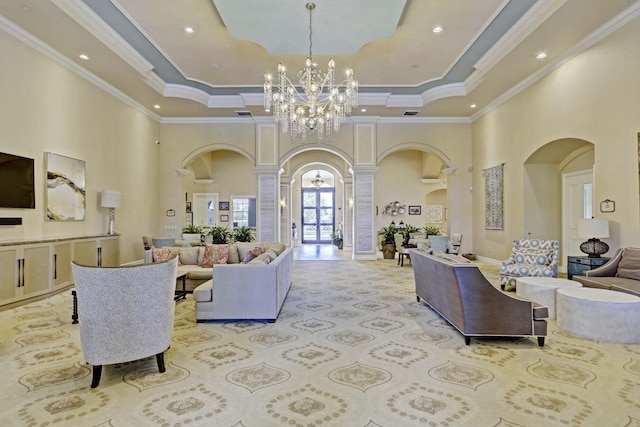 living room featuring ornamental molding, a high ceiling, decorative columns, and an inviting chandelier