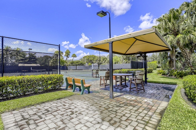 view of property's community with a patio area and tennis court