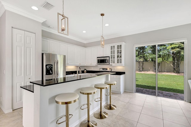 kitchen featuring white cabinets, an island with sink, stainless steel appliances, and crown molding