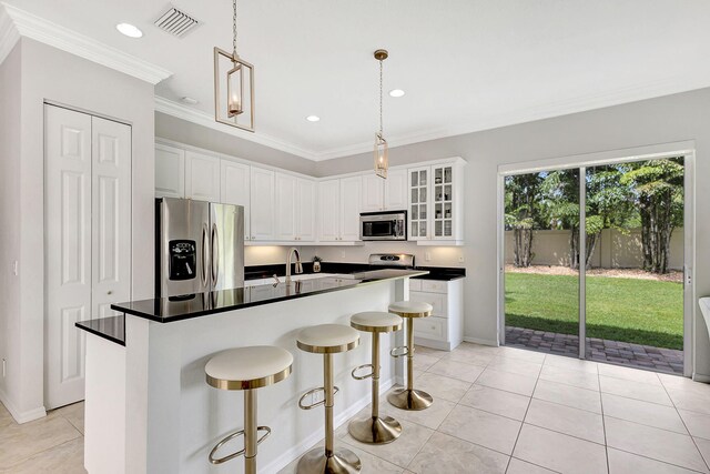 kitchen with a breakfast bar area, stainless steel appliances, visible vents, ornamental molding, and white cabinetry