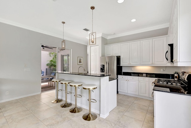 kitchen with a breakfast bar, an island with sink, white cabinets, appliances with stainless steel finishes, and ceiling fan