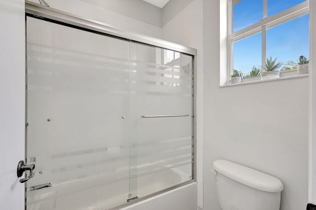 bathroom featuring toilet and combined bath / shower with glass door