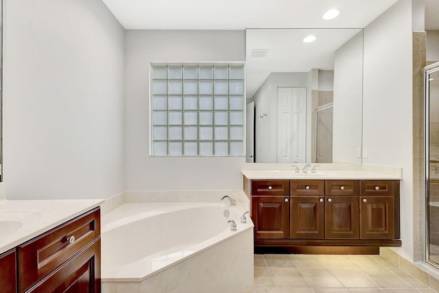 full bathroom featuring a stall shower, two vanities, and a bath