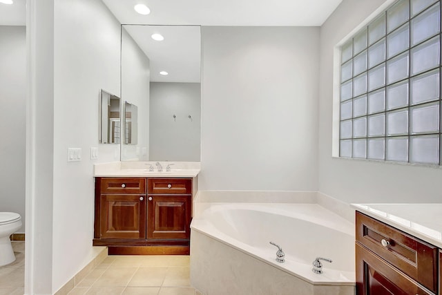 bathroom featuring tile patterned floors, a tub, vanity, and toilet