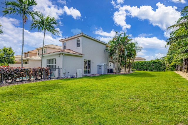 back of house with a tiled roof, a lawn, fence, and stucco siding