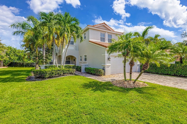 mediterranean / spanish-style house with decorative driveway, stucco siding, a garage, a tiled roof, and a front lawn