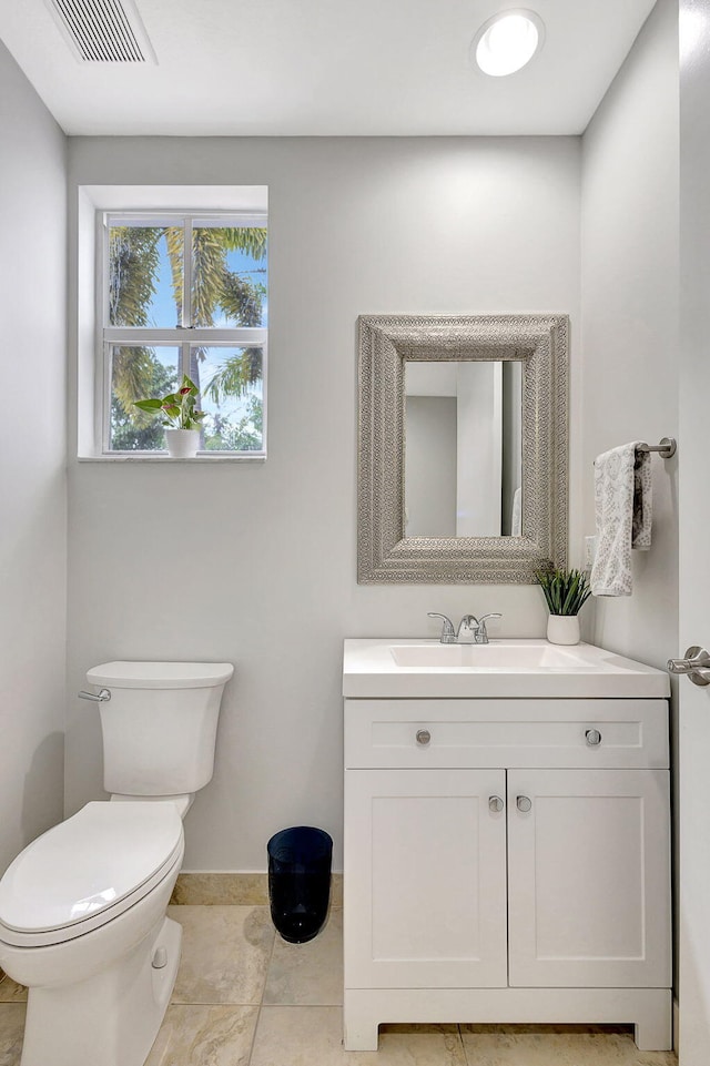 bathroom with toilet, baseboards, visible vents, and vanity