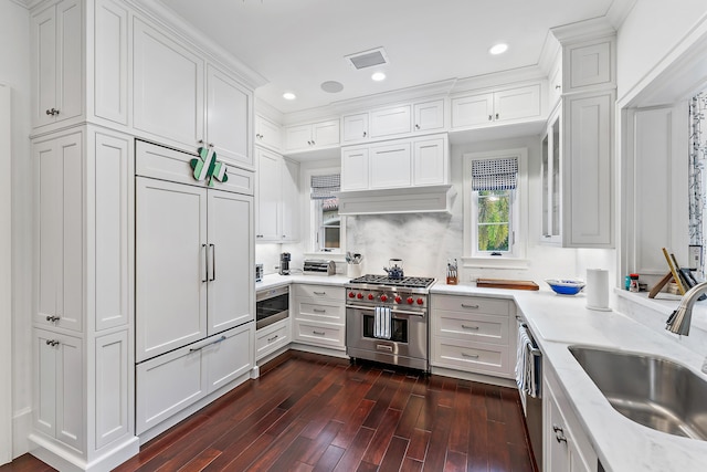 kitchen with high end appliances, crown molding, sink, white cabinets, and dark hardwood / wood-style floors