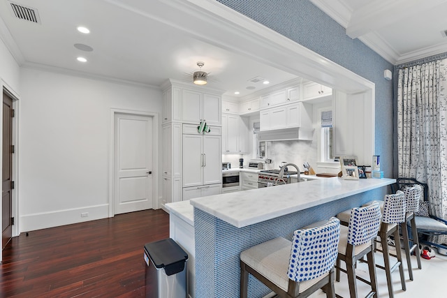 kitchen featuring kitchen peninsula, dark hardwood / wood-style floors, white cabinetry, and high quality appliances