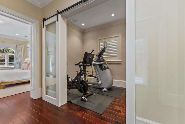 exercise room featuring a barn door, dark wood-type flooring, and ornamental molding