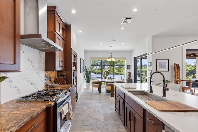 kitchen featuring backsplash, light tile patterned floors, stainless steel gas stove, sink, and wall chimney exhaust hood