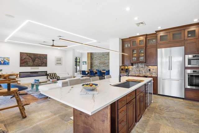 kitchen featuring sink, stainless steel appliances, light tile patterned flooring, and a center island with sink