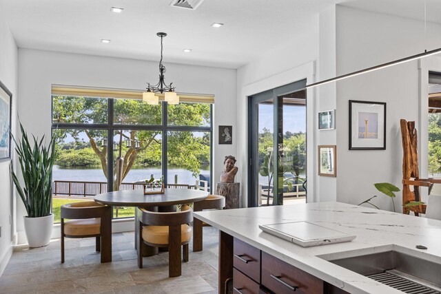 6787 Bayshore Dr, Lake Worth, FL 33462 - dining room featuring stone tile floors, a chandelier, a water view, and recessed lighting