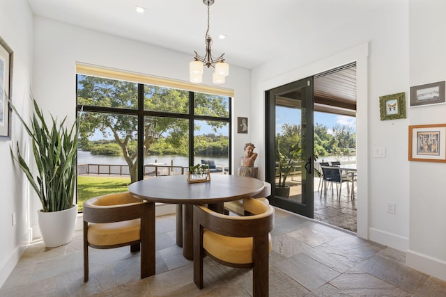 dining area with a wealth of natural light, a chandelier, tile patterned flooring, and a water view