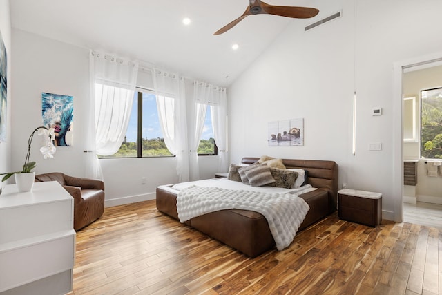 bedroom featuring high vaulted ceiling, hardwood / wood-style floors, ceiling fan, and ensuite bath