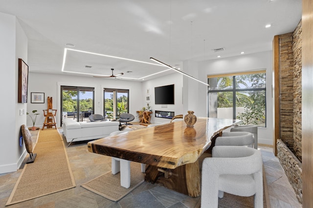 tiled dining area featuring a wealth of natural light, ceiling fan, and a stone fireplace