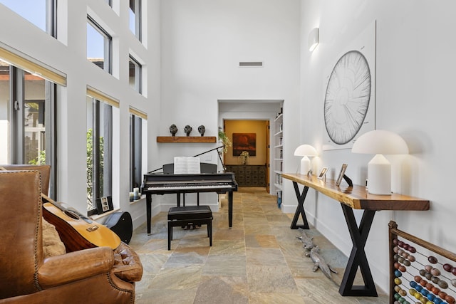 6787 Bayshore Dr, Lake Worth, FL 33462 - sitting room featuring stone tile floors, baseboards, and a towering ceiling
