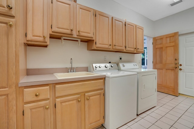 laundry area featuring light tile patterned floors, sink, washer and clothes dryer, and cabinets