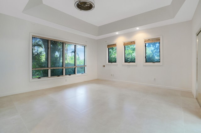 spare room with light tile patterned flooring and a raised ceiling