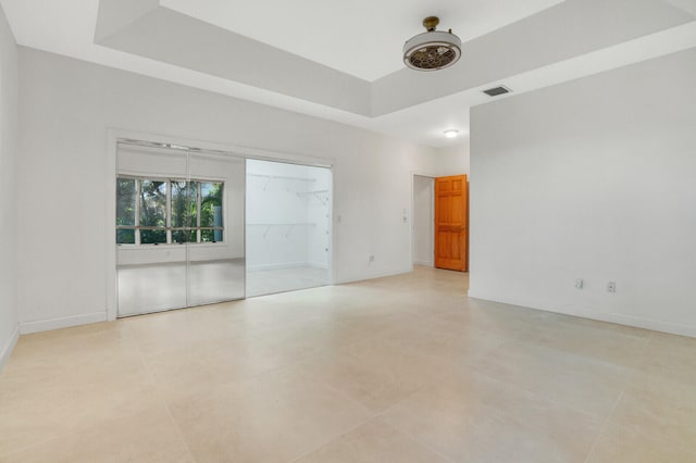 spare room featuring light tile patterned floors and a raised ceiling