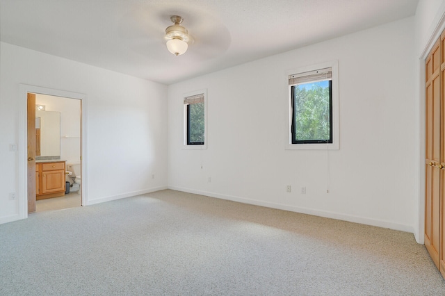 unfurnished bedroom with ceiling fan, connected bathroom, and light colored carpet