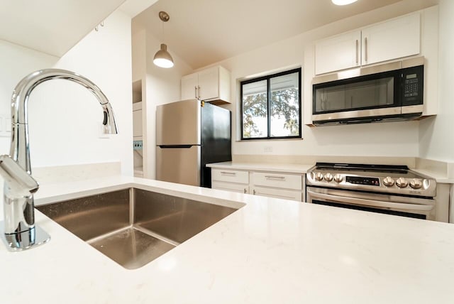 kitchen featuring white cabinetry, hanging light fixtures, appliances with stainless steel finishes, and light stone counters